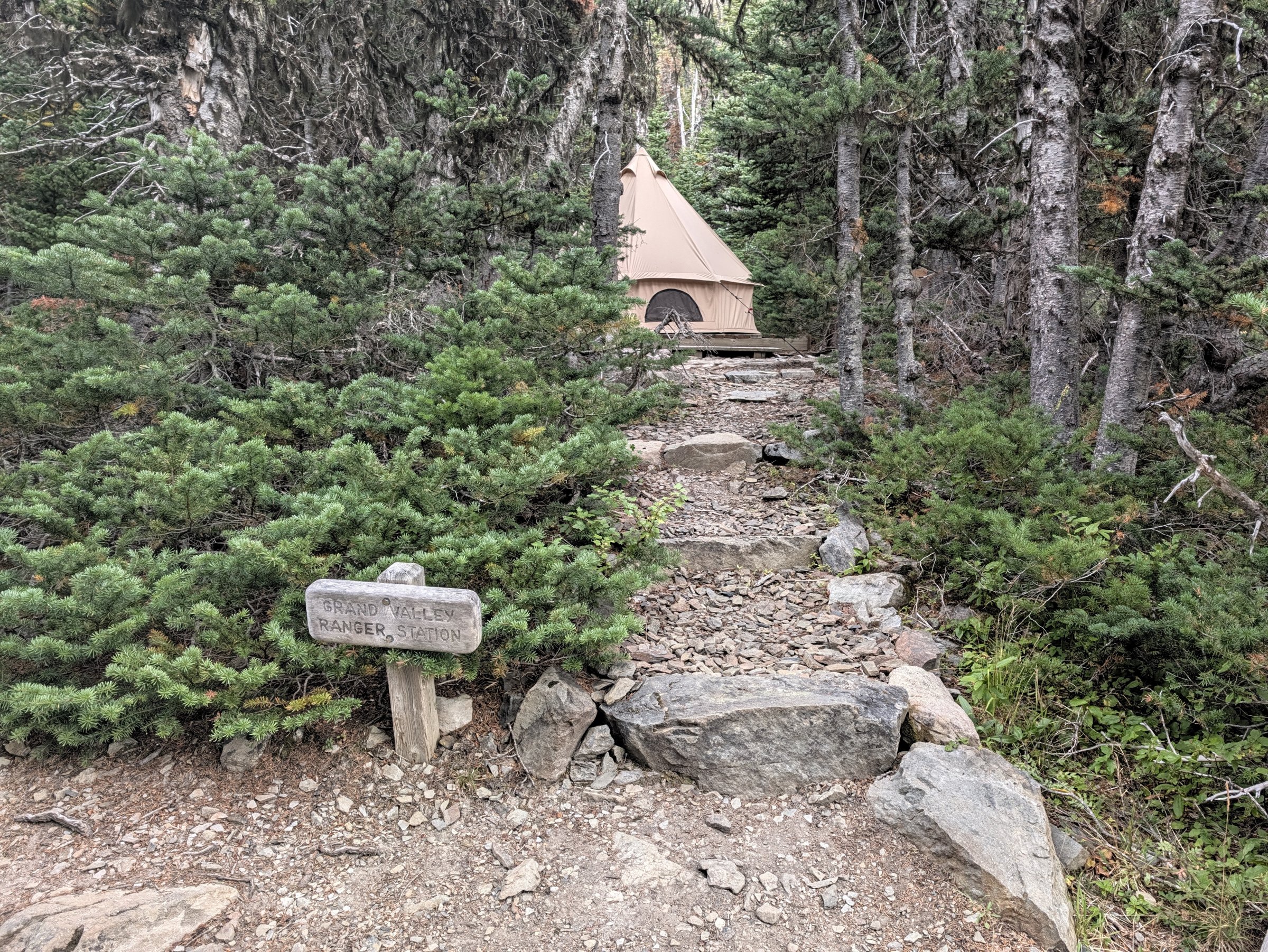 A wooden sign reading Grand Valley Ranger Station in front of a canvas wall tent in the forest